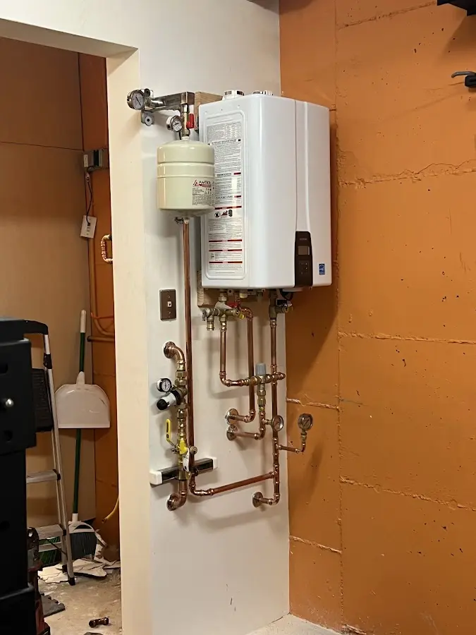 Plumbing technician inspecting water heater connections in Cedarburg